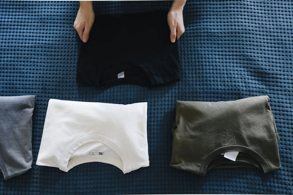 Mehrere ordentlich gefaltete T-Shirts in verschiedenen Farben auf einer Decke