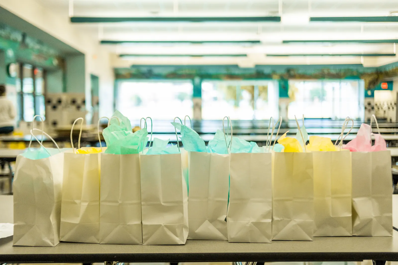 Mehrere kleine Papier-Geschenktüten stehen aufgereiht auf einem Tisch