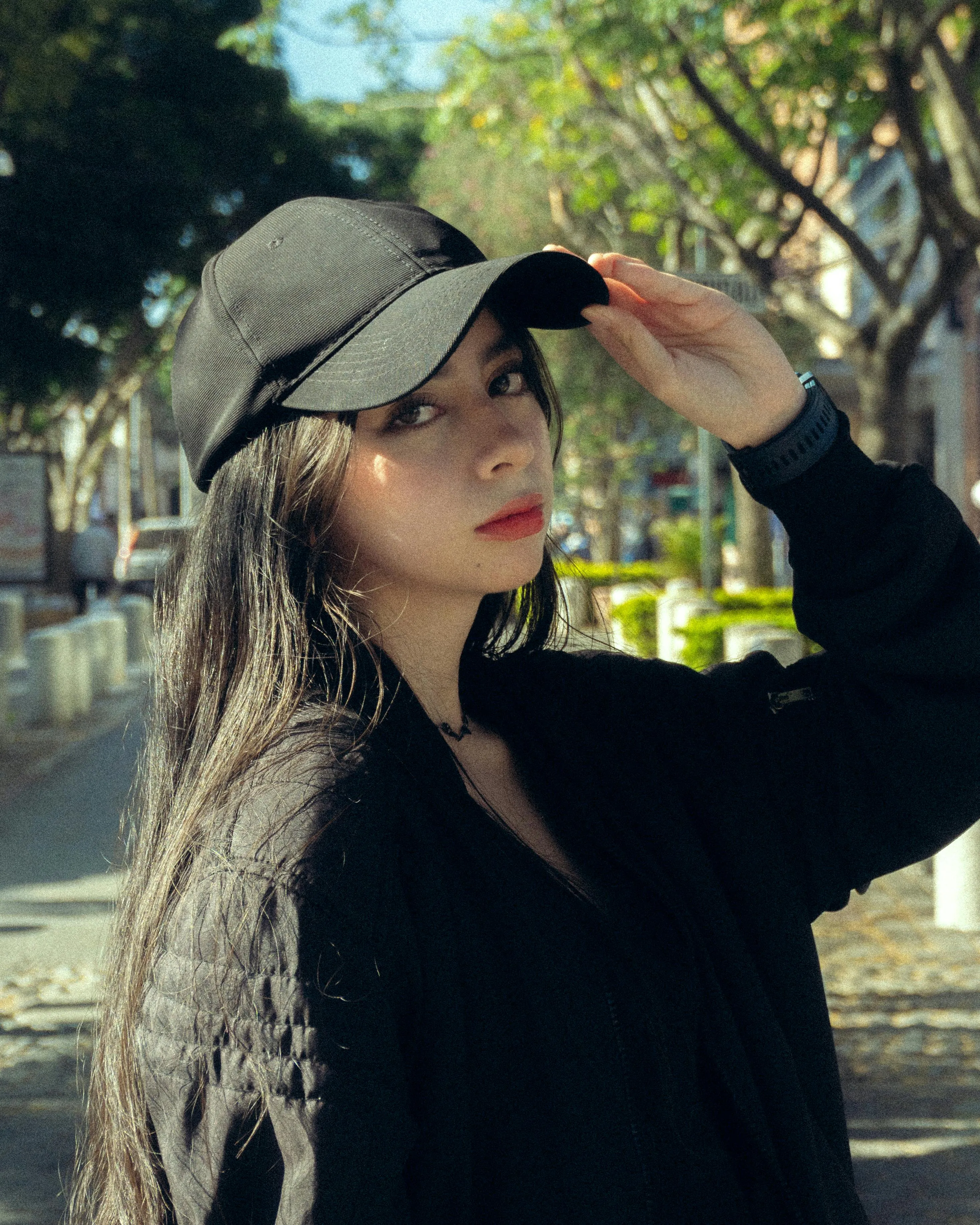 Junge Frau mit schwarzer Baseball-Cap auf einer sonnigen Straße